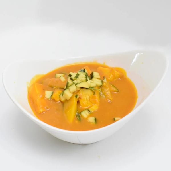 Indian pumpkin curry with diced zucchini in a white bowl.